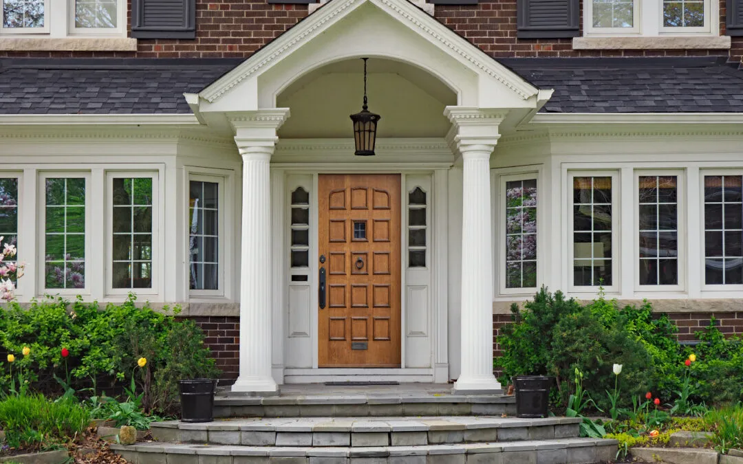 elegant wooden front door of large suburban house with gabled portico